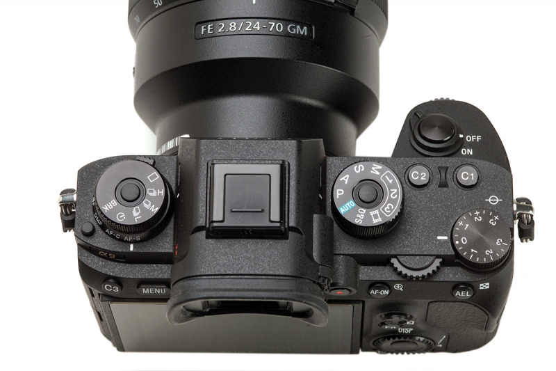 The three dials on the top of the body are combined drive and focus mode stack to the far left, a mode selection dial near the viewfinder, and an exposure compensation dial to the far right.