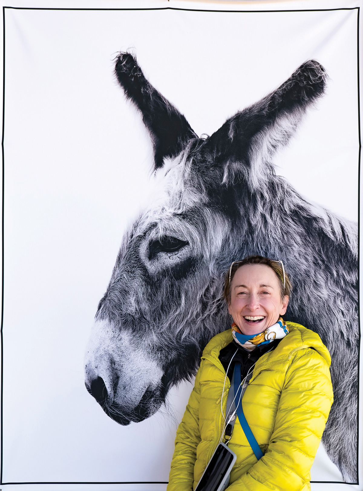 Photographer Monica Stevenson, smiling in front of a photograph of a donkey