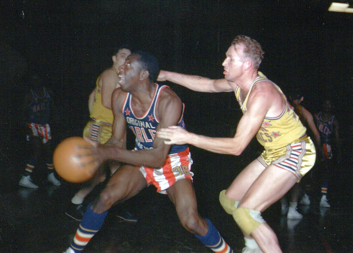 Harlem Globetrotter basketball star Goose Tatum playing against New York Celtics players, dark background