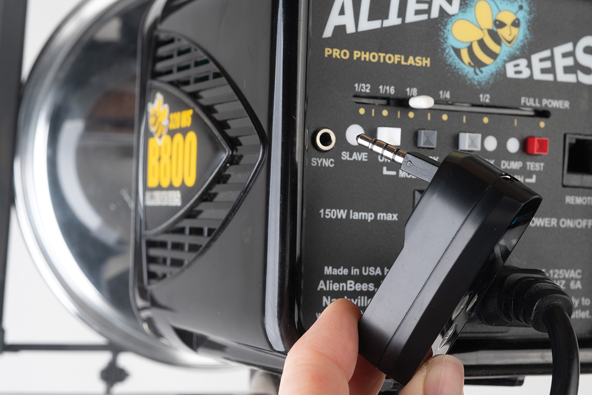 A Westcott FJ-XR Wireless Receiver held next to the 3.5mm sync port of an AlienBees B800 flash