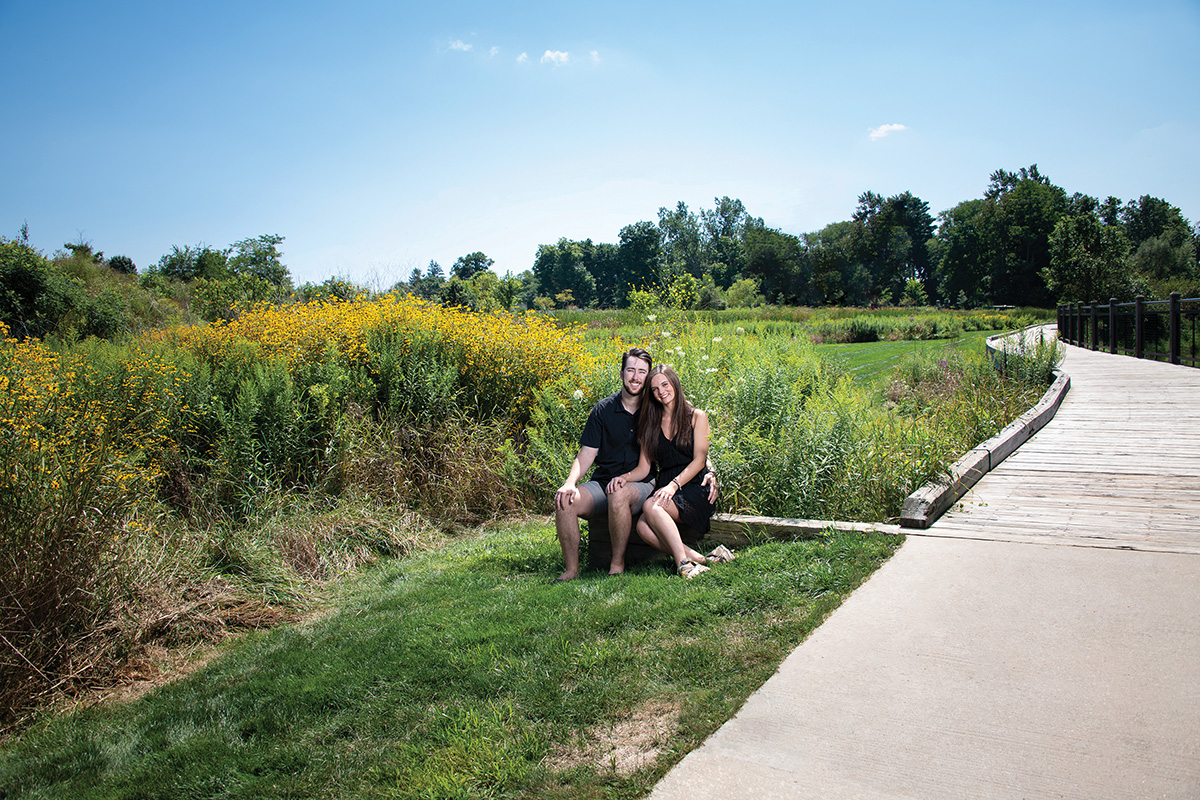 A couple sitting trailside with flowers in background. A light stand and flash has been Photoshopped out of the image. This is the second in a set of two images.