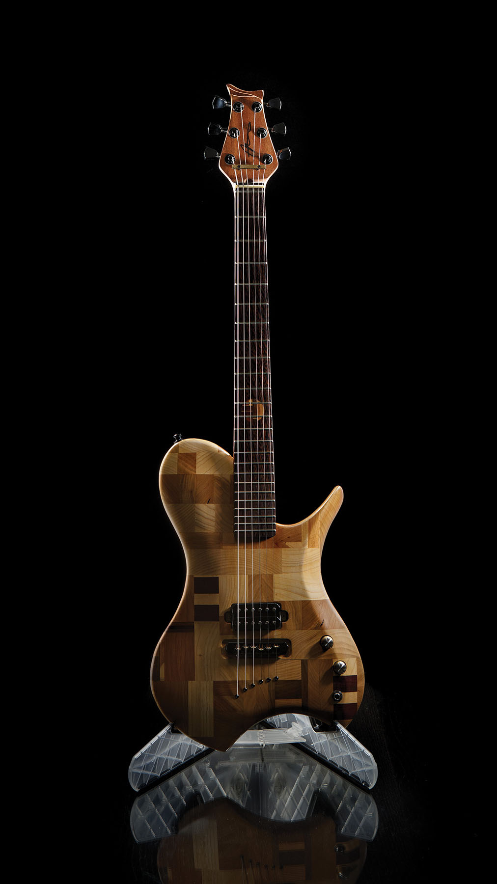 A guitar with butcher block style wood design on a black background