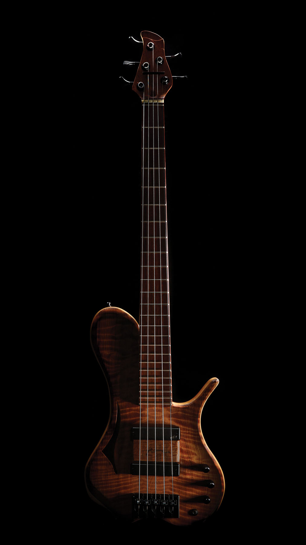 A bass guitar with stripe patterned wood on a black background