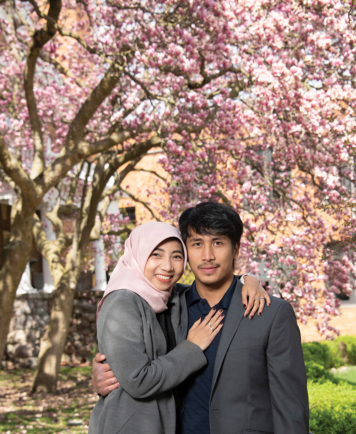 Couple in front of trees with pink blossoms