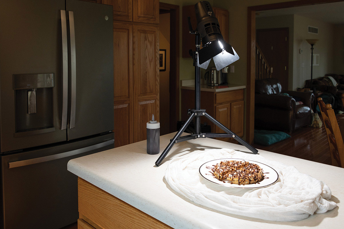 A StellaPro 2000 light with barn doors lights a still life of a waffle on a plate.