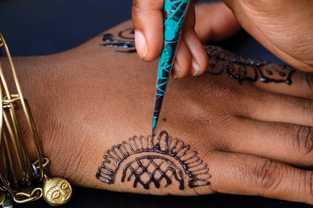 A close-up of someone applying henna to a hand