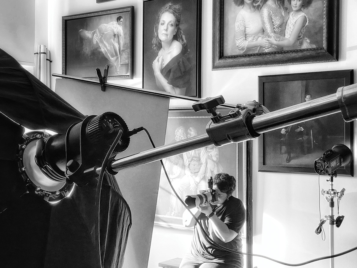 Photographer makes photos with gallery of portraits in background